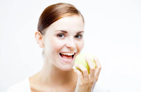 Usmívající se žena drží a jíst zelené jablko — Stock fotografie