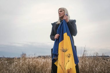Rusya 'nın Ukrayna' ya karşı savaşı. Yanık bir buğday tarlasında bayrak sallayarak koşan genç, güzel bir vatansever kız. Bağımsız bir ülkenin insanlarının karlı duygusal tablosu, acısı ve umutsuzluğu.