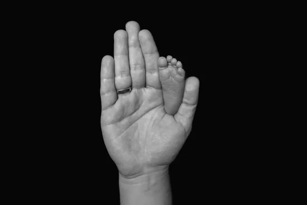 Cute little baby foot on dads big hand. Black and white card. Comparison — Zdjęcie stockowe