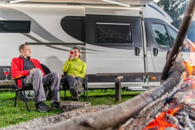 Modern karavan minibüslerinin önünde 40 'larında şarap içen beyaz bir çift. Kampın Aile Eğlencesi. Rving Teması.