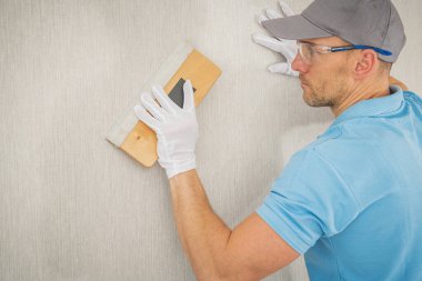 Kafkas İşçi 40 'lı yaşlarda. Yumuşak Uygulamalı Modern Vinil Duvar Kağıdı. Squeegee kullanıyor. Ev Geliştirme Teması.