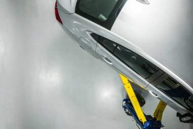 Otomotiv endüstrisi teması. Modern Silver Compact Car bir oto servisinin asansöründe. Araç Tamir ve Bakım