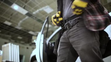 Kafkas Müteahhit İşçi Alet kemerini iş yerindeki kamyonetinin yanına takıyor..