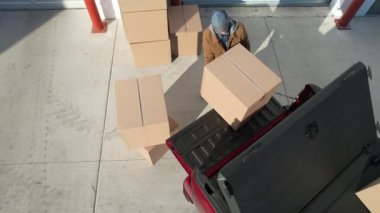 Kafkas işçisinin 40 'lı yaşlarındaki hava görüntüsü Kırmızı kamyonetini bir depo binasının yanında boşaltıyor..