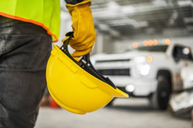 Construction Worker with Yellow Hard Hat in His Hand Inside Newly Developed Commercial Building. Staying in Front of Pickup Truck. Industrial Theme.