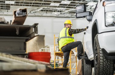 30 'lu yaşlarında Kafkas İnşaat İşçisi. Pikabını Yeni Yapılmış Depo Binası İçinde Aletleri olan Kargo Yatağını Yükleyen Şapkalı..