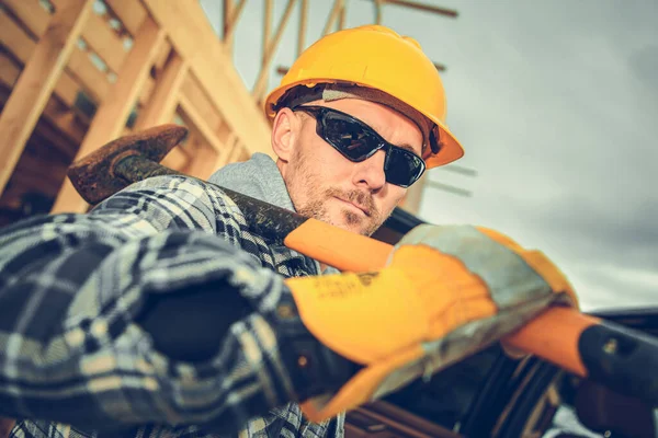 彼の肩に大きなハンマーと彼の40代の白人プロフェッショナル建設請負業者の労働者 黄色のハード帽子と目の保護サングラスを着用 — ストック写真