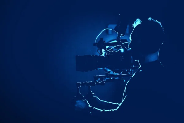 电影数码摄象机操作员在深蓝色照明电视演播室内拍摄 电视及电影业主题 — 图库照片