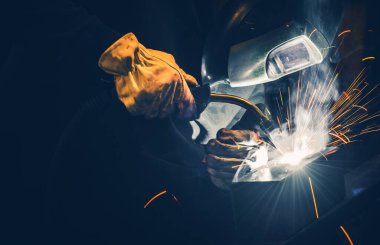 Dark Place 'te Profesyonel Kaynakçı Metal Parçalar. Sıcak Metal kıvılcımları uçuşuyor. Metal Çalışması TemasıName.