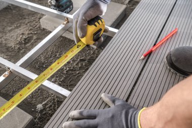 Modern Gri Bileşik Veranda Yerleri Kurulum Teması Kapatma Fotoğrafı. Yanında mezurası ve yanında bir kalem bulunan bir işçi..
