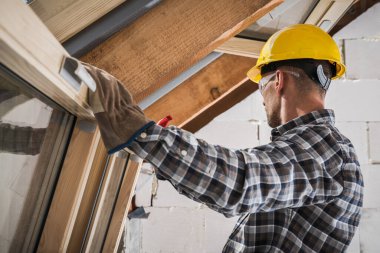 Caucasian Windows Specialist Performing Final Check. Wooden Roof Windows Installation During House Construction.