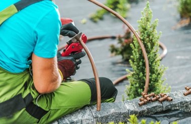 Bahçe düzenleyici Drip Sulama Bahçesi Sulama Sistemi. Plastik Sistem Boru Hattı Özel Makas Aracı kullanılarak Kesiliyor. Peyzaj Endüstrisi TemasıName.