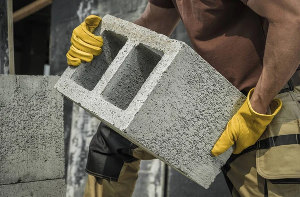 現代の中空高密度コンクリートブロックを建設現場に沿って移動する白人建設請負業者の労働者 — ストック写真