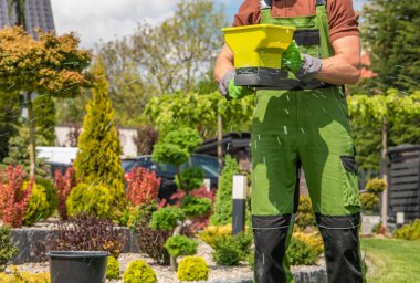 Profesyonel bahçıvan tarafından gerçekleştirilen Residential Backyard Garden Grass gübreleme.