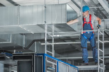 Installing Air Circulation Duct Inside a Warehouse. HVAC Technician Performing Final Check Before the Run. Commercial Heating and Cooling Systems.