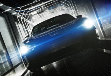 Automotive Industry Theme. Modern and Futuristic Vehicle with Blue Flares Coming From Headlights Inside a Touchless Car Wash. 