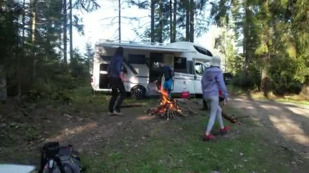 2022年5月15日ポーランド バビア Rvロードトリップ友人と休暇 キャンプファイヤーを囲んでいる2人の白人カップルホームキャンパーヴァンの隣にあります 森の中のドライキャンプ — ストック動画