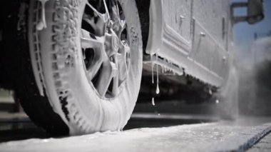 RV Camper Van Covered by Active Washing Foam Close Up Photo. Washing Recreational Vehicle Motorhome in a Car Wash.