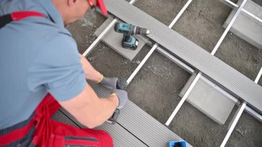 İnşaat işçisi bileşik veranda döşemesi kablosuz matkap sürücüsü kullanarak elementleri ekliyor. Endüstriyel Tema.