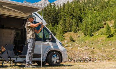 Erkekler, karavan kampçısı Van Awning 'i uzatıp geri çekiyor. Yaz Alp Kampı Kurulumu. Eğlence Araçları TemasıComment.