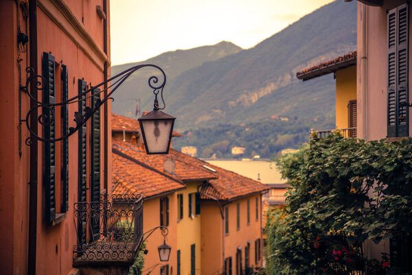 Beautiful Italian Landscape Through the Eyes of a Tourist Visiting a Small Italian Town Located Near the Mountains. Italian-Style Orange Houses with Vintage Lamps, Green Plants, Warm Summer Day.