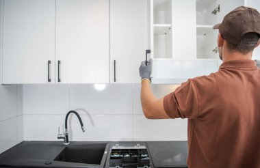 Tamirci, yeni yapılmış Duvar monte edilmiş Mutfak Deposu Dolabının Kapılarını Kontrol Ediyor. İşlerin doğru yapıldığından emin olmak için..
