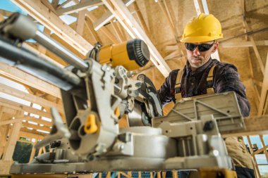 Kafkas İşçi Bir Konut Binasının Ahşap İskeleti Yapımı üzerinde çalışırken Bir Masa Testere Kullanıyor. İnşaat alanı arka planı. Tahta İnşa Teması.