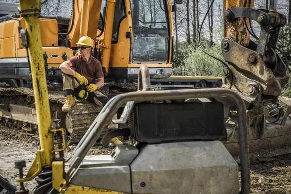 Ground Working Construction Equipment Operator Sitting on Heavy Duty Excavator Machine Taking a Break After Finishing His Job. Construction Industry Theme.