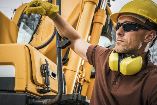 Building Supervisor Watching Over the Work In Progress at the Construction Site to Make Sure Everything Is In Order. Professional and Responsible Worker. Heavy Duty Machinery in the Background.