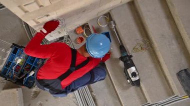 Contractor Electrician Worker Drilling Electric Outlets Holes Inside Concrete Bricks Wall of Residential Building. Construction Industry Worker Theme.
