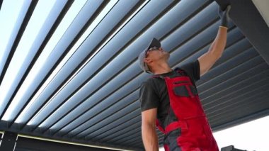 40 'lı yaşlarındaki Kafkas Teknisyeni, Otomatik Çatı Açılımlı Modern Alüminyum Ev Yapımı Pergola' nın Kurulumunu Tamamlıyor. Uzaktan Denetim Denetleniyor.