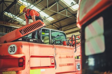 Caucasian Mechanic Checking the Digger Machine in His Heavy Duty Industrial Equipment Workshop. Regular Machinery Check and Maintenance Procedure.