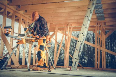 Caucasian Worker Cutting Wood with Professional Circular Saw Equipment Preparing Wooden Element for the House Frame Construction.