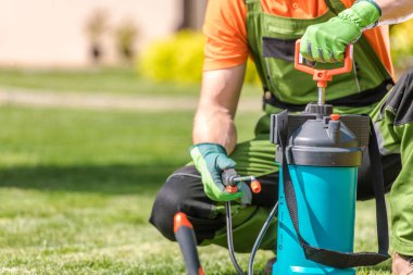 Closeup of Garden Pressure Sprayer. Professional Gardener Preparing to Spray Plants with Nutrients in the Clients Backyard Garden During Seasonal Care