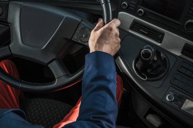 Aerial View of Drivers Sear and Control Panel in a Heavy Duty Semi Truck. Professional Trucker Holding the Steering Wheel Ready to Start the Route.