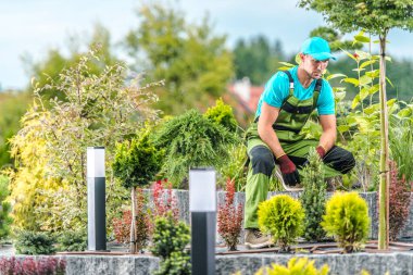 Caucasian Middle Aged Male Gardener Taking a Moment of Rest During Landscaping Large Island Bed in His Clients Backyard Garden. 