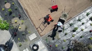 Landscaping Worker Covering Garden Weed Control Fabric with Small Decorative Rocks Aerial View. Developing Modern Backyard Garden.