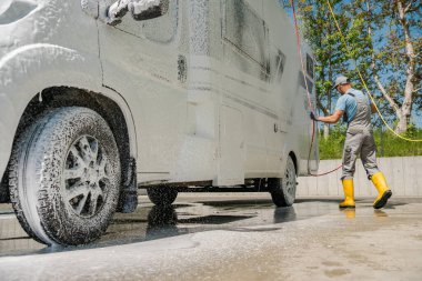 Caucasian Man Applying Active Foam While Washing His Camper Van at Self-Service Pressure Car Wash. Motorhome Care and Maintenance Theme.