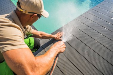 Caucasian Men Washing His Composite Material Made Swimming Pool Deck Using Garden Hose. Pool Surrounding Maintenance.