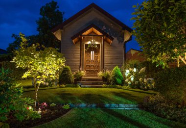 Front of Illuminated Rustic Garden Shed and Beautiful Backyard Garden with LED Lighting Installed. 