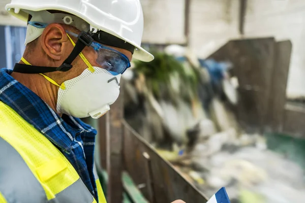 Urban Waste Sorting Facility Technician Making Documentation Staying Next to Trash Moving Conveyor.