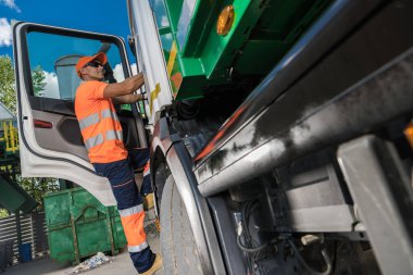 Waste Management Theme. Caucasian Garbage Truck Driver in His 40s Collecting City Garbage and Delivering to a Sorting Facility
