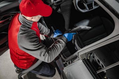 Caucasian Automotive Service Worker Cleaning Car Interior. Vacuuming Seats. Transportation Industry Theme.