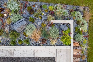 Aerial View of Landscaped Garden Corner Decorated with Pebbles, Stones, Wood and Various Types of Shrubs. Landscaping Design Theme.