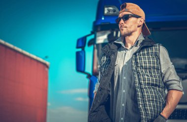 Caucasian Heavy Duty Semi-Trailer Truck Driver in His 40s Patiently Waiting at the Logistic Center Parking to Receive the Cargo for Long Distance Delivery.
