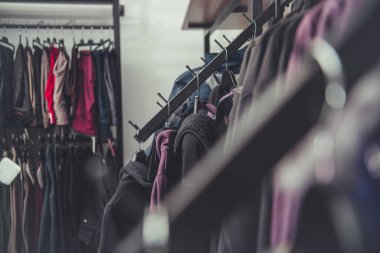 Closeup of Racks Full of Different Types of Clothes on Hangers in Second Hand Shop. Pre-Owned Wear Shopping Theme.