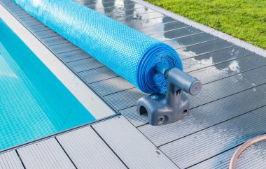 Manual Outdoor Swimming Pool Solar Blanket Cover Roller or Reel Close Up. Maintenance Water Temperature and Cleanliness.