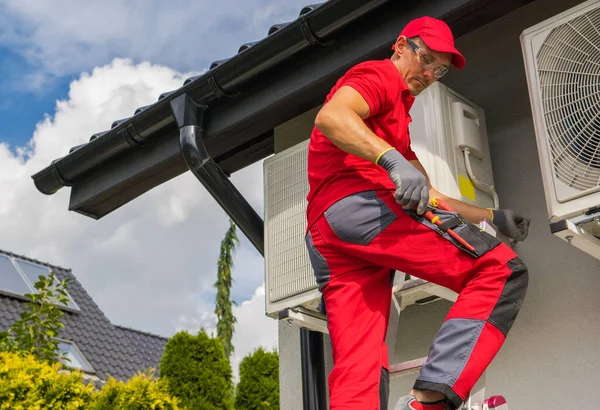 現代の家庭用暖房技術 40代のプロ白人のHvac労働者は はしごからヒートポンプの修理を維持 — ストック写真