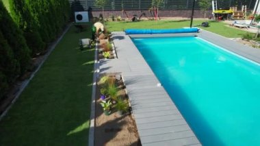 Poolside Natural Grass Turfs Installation. Cart with Fresh Turfs Staying Next to Swimming Pool. Landscaping Job.