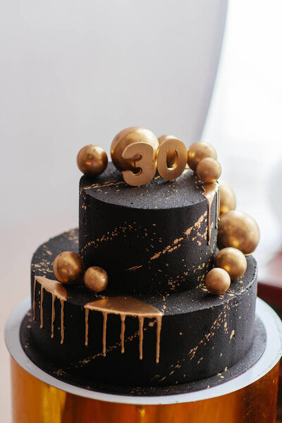 Chocolate birthday cake with gold decorations. Holiday, celebration, stylish, minimal concept.
